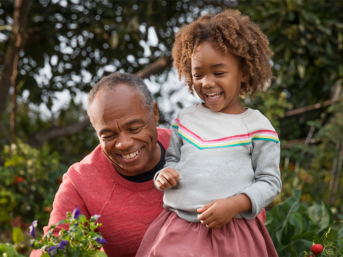 Man and young girl smiling outside.