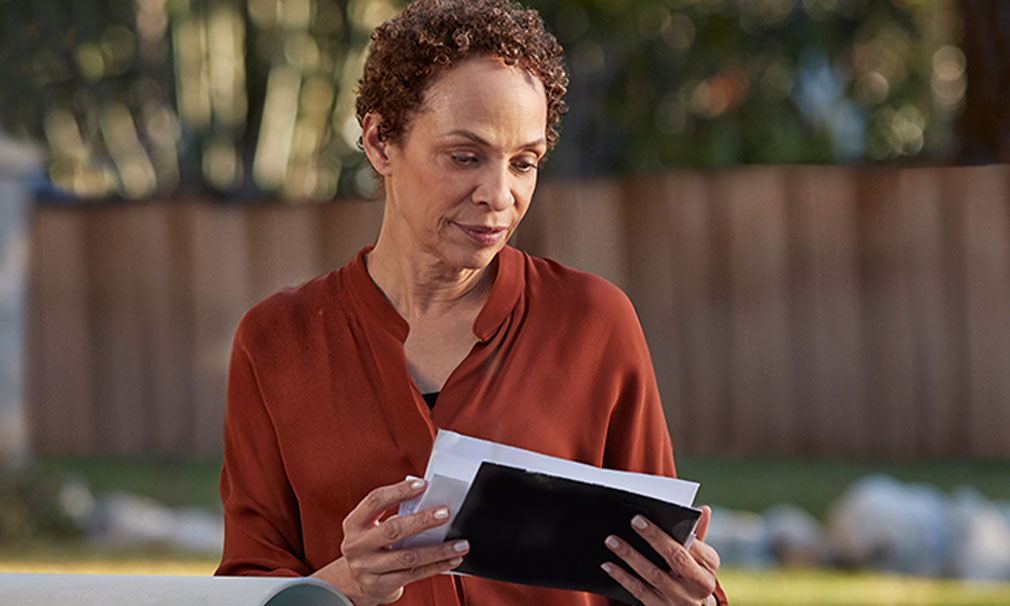 Woman sitting outside looking at a piece of paper.