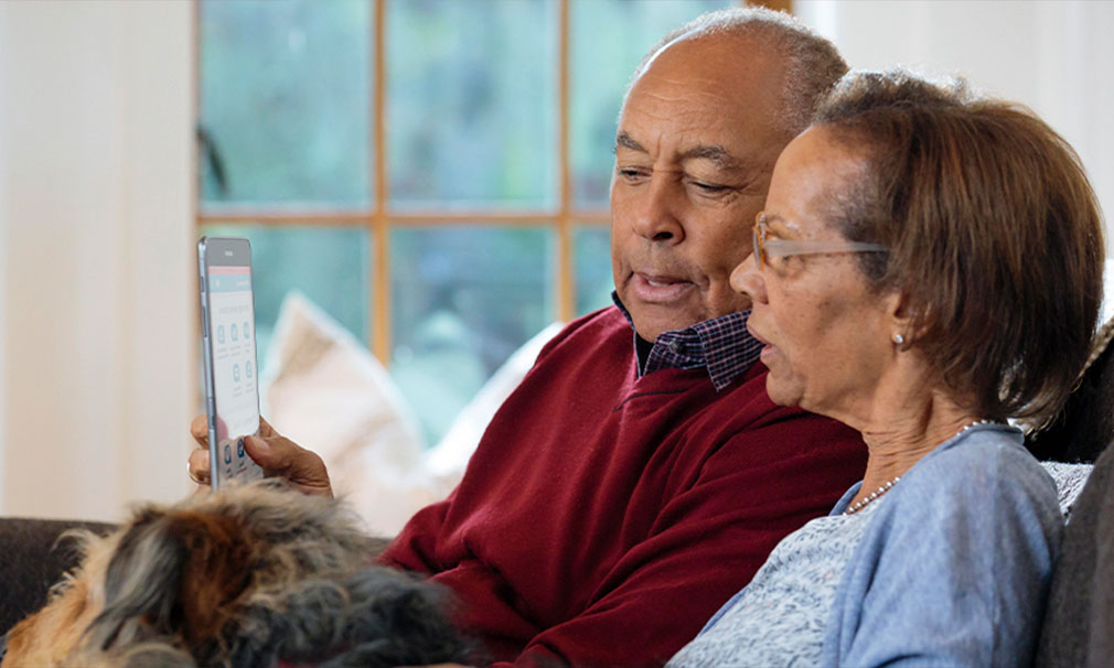 Female and male sitting on a couch together viewing a laptop screen.