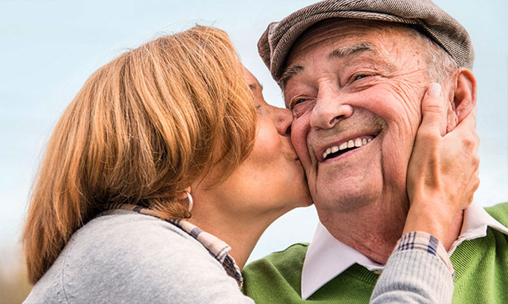 Woman kissing a man on the cheek as he smiles.