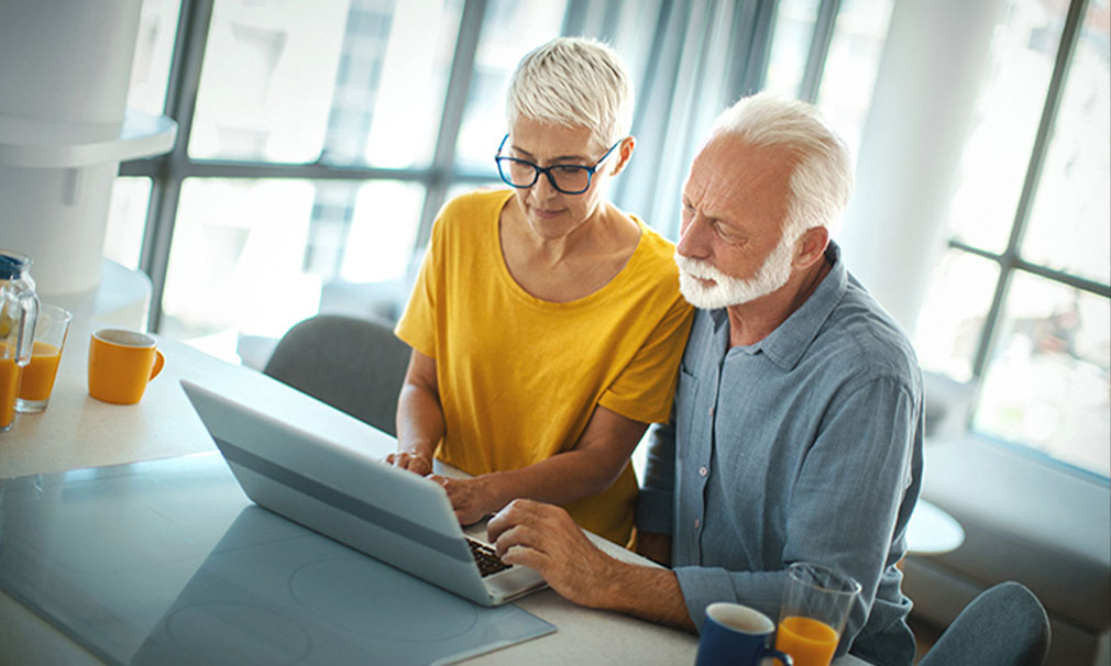 Male and female standing next to each other viewing a laptop.